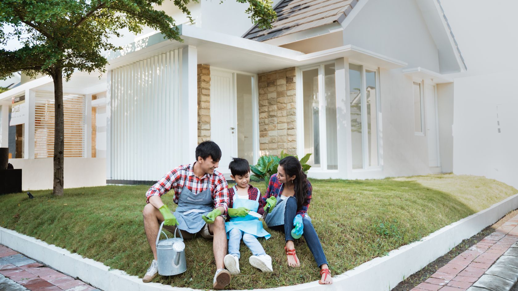 Family sitting on grass in front a brand new home