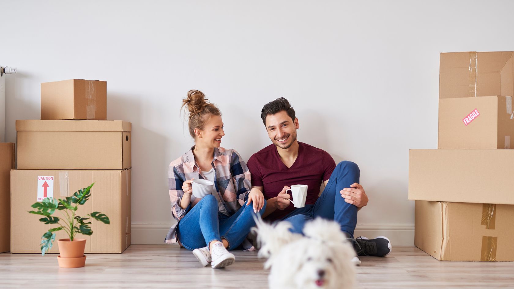 Image of a couple sitting beside boxes, unpacking after securing successful financing