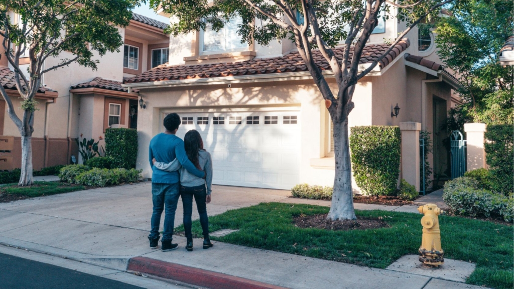 Couple standing in front of a house on a sunny summer day