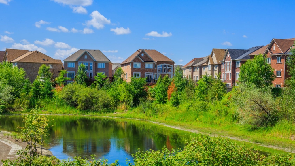 Houses surrounded by greenery in front of a pond